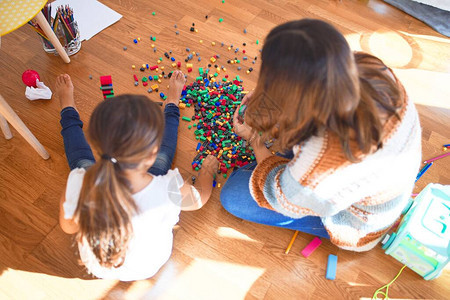 漂亮的老师和幼儿在幼儿园的许多玩具周图片