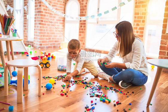 美的老师和幼稚园儿童在幼儿园玩许多玩具的图片