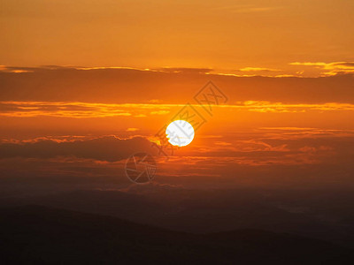 明亮的太阳和戏剧日出天空山底有橙图片