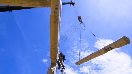 在阳光明媚的日子里施工初期的木屋顶建筑工人用起重机安装图片