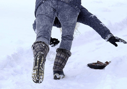 一个女人滑倒在雪覆图片