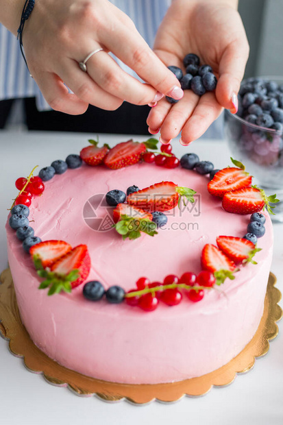 贝克给蛋糕加蓝莓女人装饰美味蛋糕女孩生日奶油图片