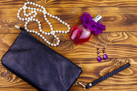 木制背景上的女配饰木桌上的手拿包香水瓶珍珠项链和耳环美容和时尚组成图片