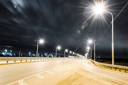明亮的灯光和曝光线照亮的夜间高速公路有排气管的工厂月亮和星图片