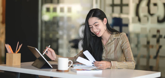 年轻的职业女设计师在现代办公室使用数字平板电脑时图片