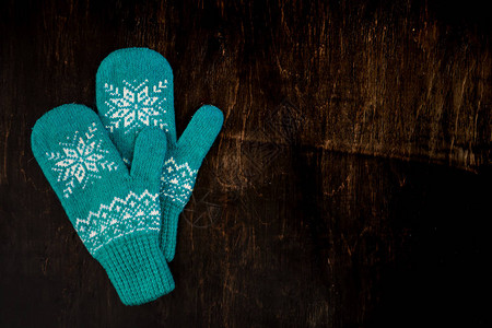 一对蓝色编织的手套印在深蓝绿褐色木质古董背景图片