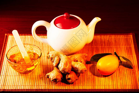 在竹子的餐巾纸上放着装有姜黄蜂蜜生姜的杯子一杯加牛奶白色茶壶图片