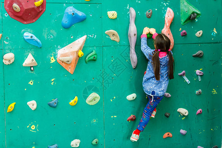 带攀岩墙的休闲公园里的小女孩登山者背景图片