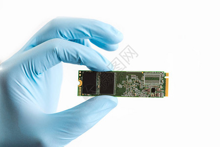 蓝色手套的大师手拿着白色背景的ssd磁盘硬M2SSD磁盘用于高速数据存储背景图片