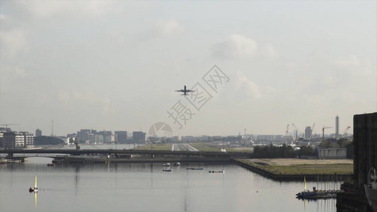 飞机在多云的天空背景下飞越城市桥梁和宽阔的河流飞机起飞旅图片