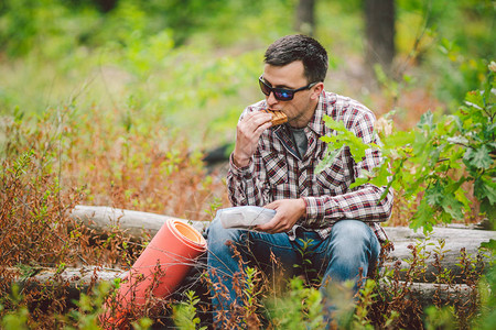 饥饿的人吃东西户外三明治的徒步旅行者坐在森林里吃三明治游客吃零食徒步旅行者休息时间吃饭白种人旅游带三图片