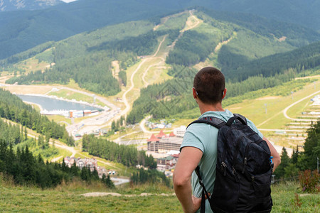 男子旅行者背着包站在山顶上与村庄一起图片