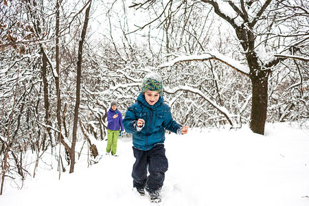 男孩在雪路上逃离他的母亲男孩和妈一起走在白雪覆盖的森林小路上寒假一个孩子和他的妈图片