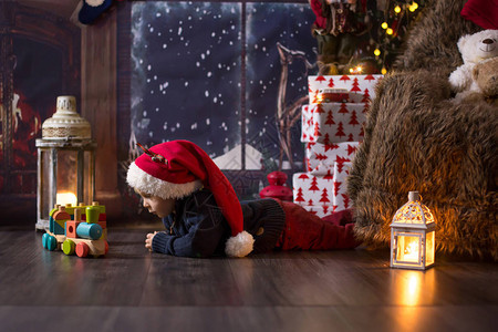 可爱的小孩男在圣诞节晚上在家玩木火车图片