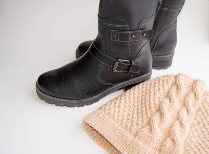 时尚冬季女鞋黑色皮靴和白色背景上的针织羊毛帽图片