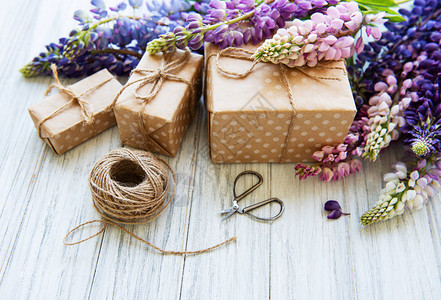 白色木制背景和礼品盒上的羽扇豆花图片