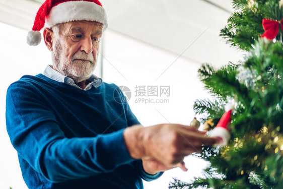 老人在庆祝新年前夜时放松装饰圣诞树图片
