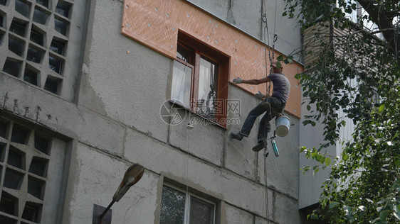 房屋墙隔绝工人悬吊在绳索上图片