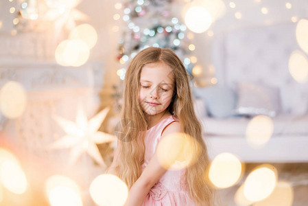 一个金发长头发的女孩许愿梦想在圣诞树背景上做梦图片