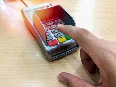 指向没有木制桌子卡的付款机器上的号码扣子手指头背景图片