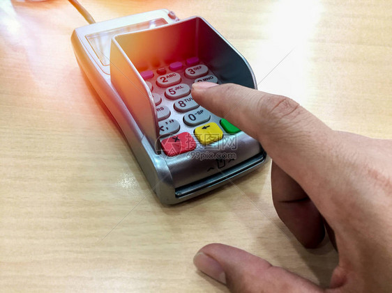 指向没有木制桌子卡的付款机器上的号码扣子手指头图片