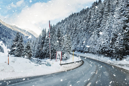 冬季高山道路曲线景观与森林山脉和蓝天背景在明亮寒冷的暮光之城汽车旅行家庭旅行之旅假日滑雪假期风景秀背景图片