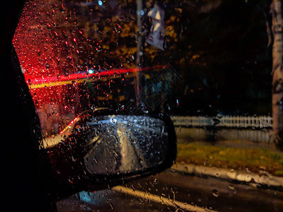 红色汽车和雨滴的特写聚焦在带有侧后视镜图片