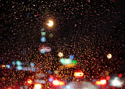 汽车挡风玻璃上满是雨滴夜里市区街道交通图片