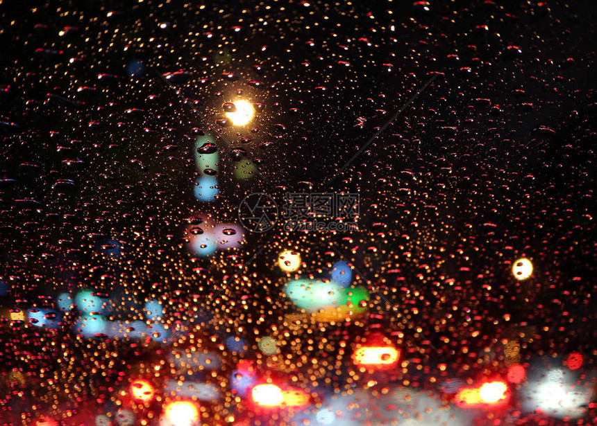 汽车挡风玻璃上满是雨滴夜里市区街道交通图片