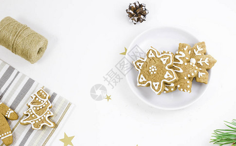姜饼以男人圣诞树和雪花的形式放在餐巾纸和白色背景的盘子上图片