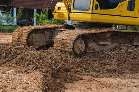 在建筑工地的黄色挖掘机反对蓝天重工业关闭工业挖掘机的细节大型履带式挖掘机站在橙色地面上图片