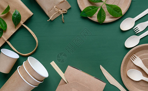 绿色木桌上用纸制成的环保一次餐具图片