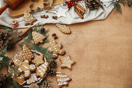 老式盘子上的圣诞姜饼和八角肉桂松果和雪松树枝在质朴的桌子上图片