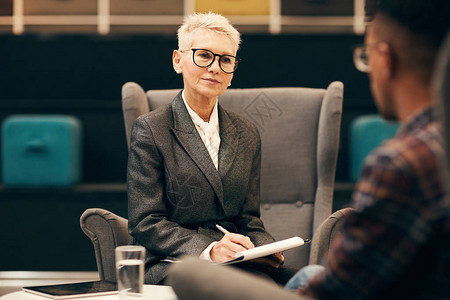 金发短戴眼镜的成熟女商人在商务会议期间采访年轻人图片