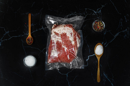 盐和肉是黑色背景上的真空包装香料图片