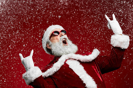 跳起冷酷摇滚的肖像圣诞老人在红背景上咆哮降图片