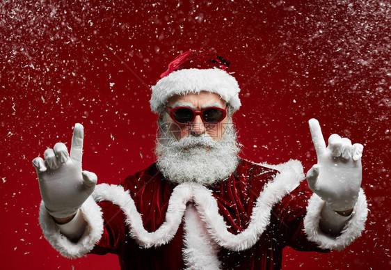 穿着太阳眼镜的酷圣诞老人在雪中享受圣诞晚会时微笑着图片