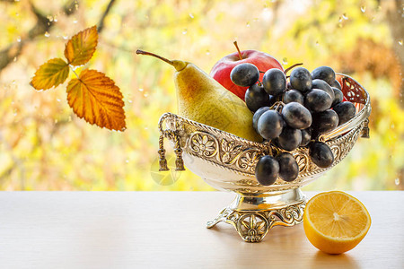 有黄色梨子葡萄和柠檬的金属花瓶图片