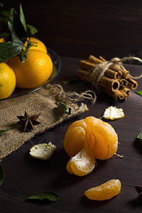 木制桌边的红番茄加鲜橙色橘子和木制背景的绿叶图片