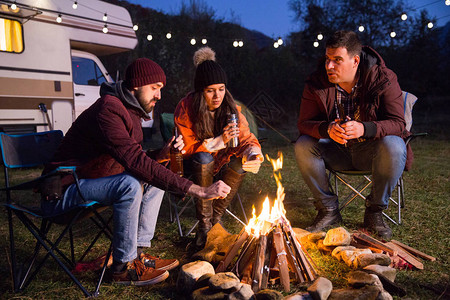 露营者在营地的火和啤酒周围一起放松背景图片