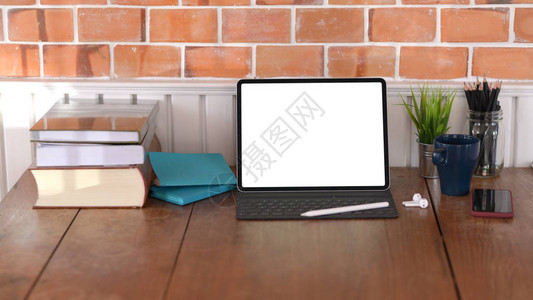 木桌和砖墙背景上带有空白屏幕数字平板电脑和办公用品的复古工作图片