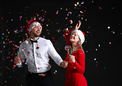 圣诞老人帽子的幸福情侣和深底面香槟图片