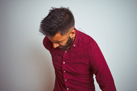 身穿红色优雅衬衫的印度年轻男子站在孤立的灰色背景上背痛用手触摸背图片