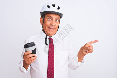身戴自行车头盔的高级商人在孤立的白人背景上喝咖啡图片
