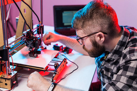 年轻的男设计师工程师在实验室使用3D打印机并研究产品原型技图片