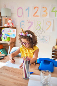 在幼儿园用纸笔和标志笔坐在桌边绘画时图片