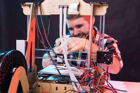 年轻的男设计师工程师在实验室使用3D打印机并研究产品原型技图片