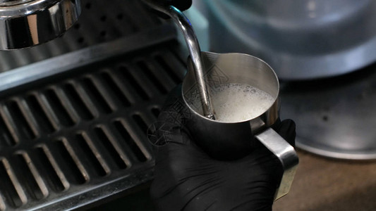 咖啡师在工作制作咖啡和可的过程一杯起泡的牛奶电动研磨机在过滤器支架图片
