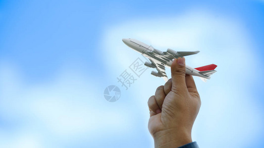 年轻的亚洲人拿着微型玩具飞机在云蓝天背景上飞行夏季乘飞机旅行和旅行图片