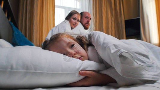 酒店房间里的一家人一个睡在床上的女孩她的爸妈图片